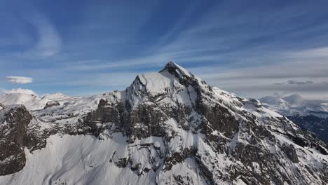 Vista-Aérea-Del-Pico-Fronalpstock-Cubierto-De-Nieve-Con-Acantilados-Escarpados-Y-Un-Cielo-Azul-Claro-En-Glarus-Nord,-Suiza