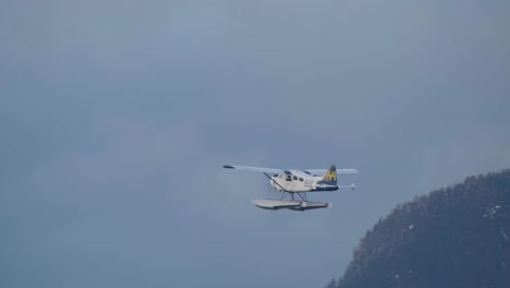 Ein-Flugboot-Schwebt-Hoch-über-Brockton-Point,-Stanley-Park-In-Vancouver,-British-Columbia,-Mit-Majestätischen-Bergen-Im-Hintergrund---Schwenkaufnahme