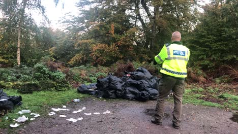 Illegale-Müllentsorgung-Im-Englischen-Epping-Forest.-Polizist-Fotografiert-Müllhaufen,-Der-Auf-Parkplatz-Abgeladen-Wurde