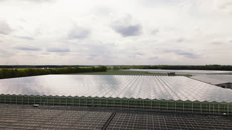 Solar-panel-farm-and-massive-greenhouses,-aerial-drone-view