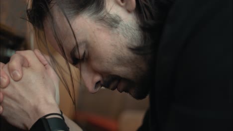 Young-man-in-black-suit-praying-in-church-in-cinematic-slow-motion