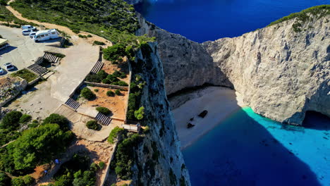 AERIAL-People-at-the-viewpoint-of-the-Navagio-Beach,-in-sunny-Zakynthos,-Greece