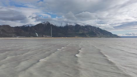 Wide-Great-Salt-Lake-aerial-with-large-copper-mine-smelter-stack-in-background-on-a-sunny-day