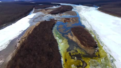 Ein-Großer-Gebirgsfluss-Taut-In-Einer-Sonnigen-Quelle-Aus-Dem-Eis-Auf,-Aus-Der-Vogelperspektive