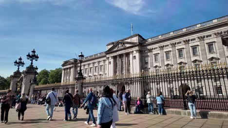 An-Einem-Sonnigen-Morgen-In-London,-England,-Schlendern-Menschen-Vor-Dem-Buckingham-Palace-Entlang-Und-Genießen-Die-Lebendigkeit-Des-Stadtlebens-Und-Den-Reiz-Berühmter-Wahrzeichen