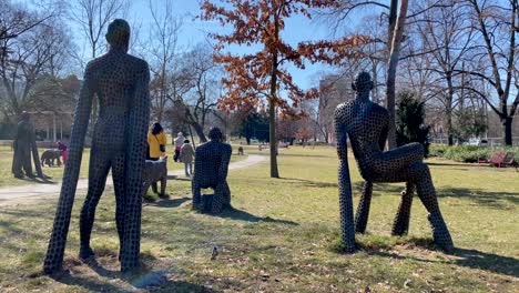 People-Walking-In-The-Park-Komenskeho,-Comenius-Park-With-Bronze-Sculptures-By-Sculptor-Michal-Gabriel-In-Zlin,-Czech-Republic