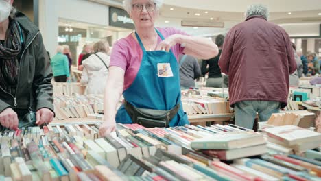 A-Old-Woman-with-White-Hair-Looks-Smiles-and-See-Childrens-Hospital-Charity-Logo-in-a-Mall-Used-Book-Sale