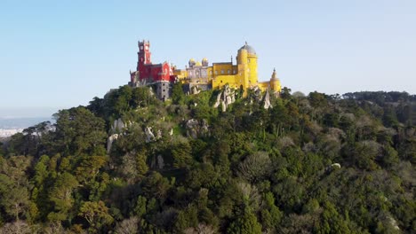 Wide-Shot-of-Colorful-Pena-Palace-in-Sintra,-Portugal:-Aerial-Drone-View,-Looking-Down-From-Above-at-Bright-Castle-Near-Lisbon,-Bright-Sunny-Day