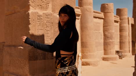 Una-Joven-Y-Hermosa-Asiática-Visita-El-Complejo-Del-Templo-De-Philae-Con-Un-Largo-Vestido-Negro-Que-Parece-Cleopatra.