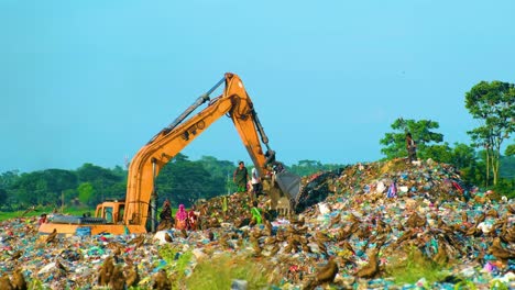 Excavadora-En-Un-Vertedero-En-Dhaka,-Bangladesh,-Pájaros-águila-Volando,-Plano-Amplio