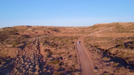 Aerial-view-drone-of-white-van-driving-through-desert-road