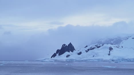 Montañas-Invernales-Al-Atardecer-Y-Océano-En-La-Antártida-Con-Nubes-Y-Cielo-Dramáticos,-Paisajes-Increíbles-En-La-Costa-De-La-Península-Antártica,-Paisajes-Costeros-Al-Atardecer-En-Una-Escena-Nevada-Helada-En-Clima-Frío