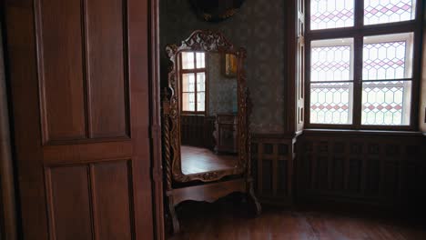 Pequeña-Biblioteca-En-El-Castillo-De-Trakošćan,-Croacia,-Con-Un-Espejo-De-Madera-Ornamentado-Y-Vidrieras