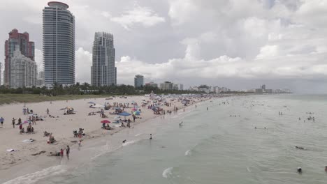 Beach-goers-on-Miami-South-Beach-in-low-aerial-from-stone-breakwater