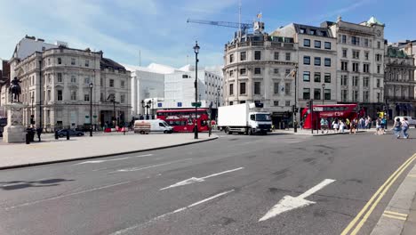 Shot-of-famous-double-decker-buses-passing-by-Trafalgar-square-in-London,-England