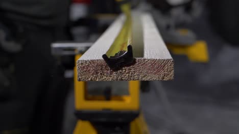 Slow-motion-footage-of-a-carpenter-using-a-tape-measure-on-a-piece-of-wood-before-sawing-it