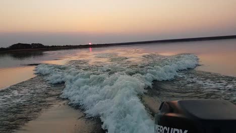 Vista-Desde-Detrás-De-Un-Barco-De-Lubina-Acelerando-Con-Una-Impresionante-Puesta-De-Sol-En-La-Distancia