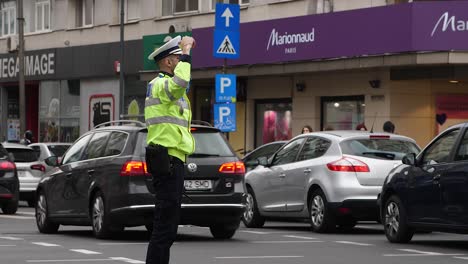 Oficial-De-Tráfico-Dirigiendo-Coches-En-Una-Concurrida-Intersección-De-Bucarest,-Con-Chaqueta-De-Alta-Visibilidad