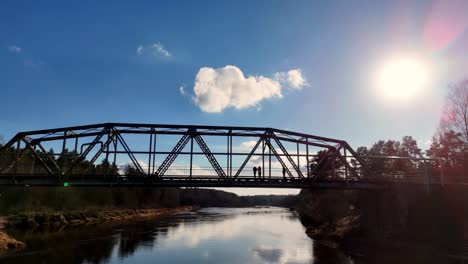 Gente-En-Silueta-Mirando-Hacia-Abajo-Sobre-El-Río-Gauja-Desde-El-Puente-Ainazi-smiltene-En-Valmiera,-Letonia