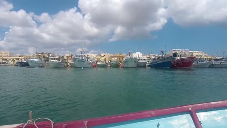 Huge-Boats-Moored-At-Maritime-Sea-Port-in-Valletta,-Malta,-Dolly-View-from-Passing-Boat,-Handheld