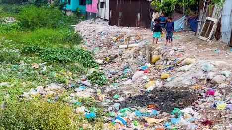 Kinder-In-Der-Nähe-Einer-Schmutzigen,-Verschmutzten-Mülldeponie-In-Der-Nähe-Von-Siedlungen-In-Der-Stadt-Dhaka,-Bangladesch