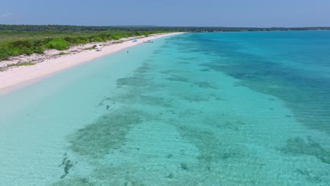 Turquoise-bay-of-Aguilas-in-Pedernales,-with-coral-reef-and-green-island-in-summer