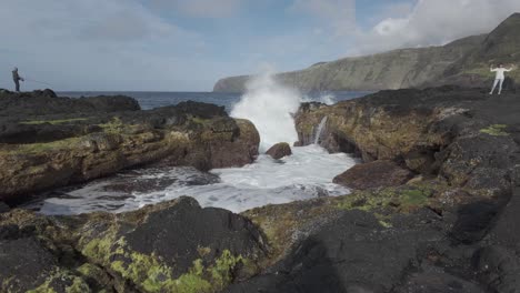 Man-explores-rocky-coast-of-Mosteiros,-Sao-Miguel-with-waves-crashing-dramatically