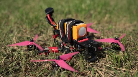 Closeup-Of-An-FPV-Drone-On-Grass-Field-With-Propellers-Spinning