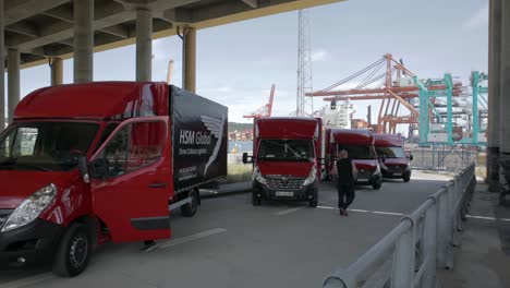 Drivers-get-into-HSM-Global-delivery-trucks-parked-under-bridge,-static-shot