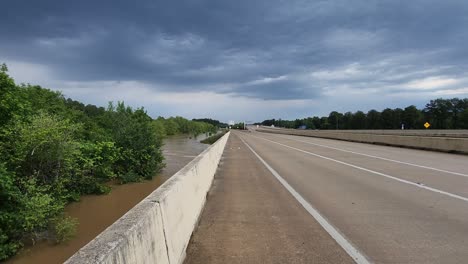 This-video-shows-brown-water,-flooding-streets-below-the-highway,-with-cars-driving-on-the-highway,-safe-from-the-water