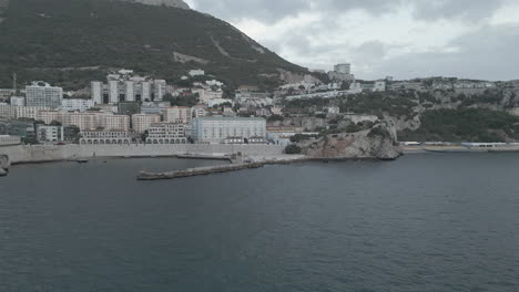 A-4K-shot-at-sunset-on-a-dark-and-cloudy-day,-from-a-drone-flying-from-the-bay-of-Gibraltar-towards-Gibraltar's-Rosia-bay