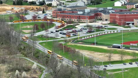 Driving-yellow-school-buses-on-road-in-front-of-American-school