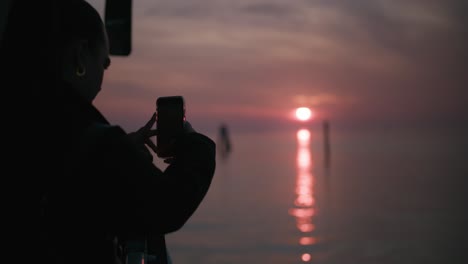 Sonnenuntergang-Auf-Der-Insel-Burano-Einfangen,-Silhouette-Einer-Person,-Die-Ein-Foto-über-Ruhigem-Wasser-Macht