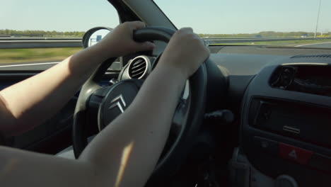 close-up-shot-from-the-passenger-seat-of-woman-hands-holding-the-driving-wheel-to-drive-the-car-on-the-high-speed-highway