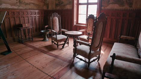 Small-Salon-in-Trakošćan-Castle-,-Croatia,-featuring-ornate-wooden-furniture-and-wall-paintings