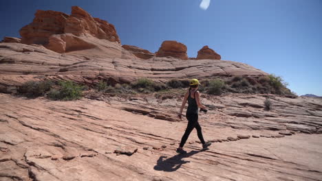 Female-Landscape-Photographer-Walking-on-Sandstone-Hill-in-Grand-Canyon-National-Park,-Arizona-USA