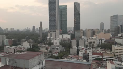 Sentada-En-Una-Azotea,-Una-Persona-Contempla-Los-Rascacielos-De-La-Ciudad-De-México-Mientras-Un-Dron-Despega