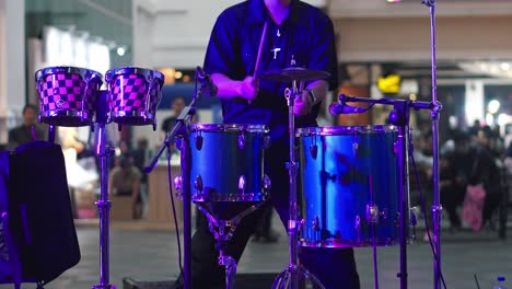 Man-playing-drums-and-hitting-cymbals-during-perform-on-stage-at-music-concert