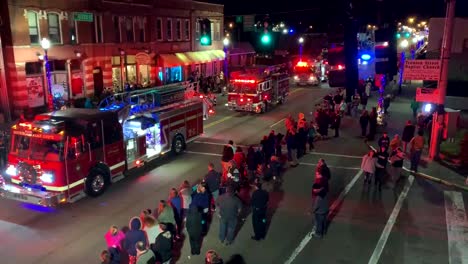 Feuerwehrautos-Und-Ein-Polizeiauto-Fahren-Nachts-Bei-Einer-Weihnachtsparade-Die-Hauptstraße-Der-Stadt-Entlang