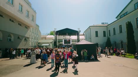 Audience-of-student-pupil-and-teacher-at-high-school-courtyard-in-front-of-stage-listening-to-concert-social-event