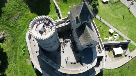 Medieval-castle-with-a-tower,-walls,-and-courtyard-during-a-beautiful-summer-day-surrounded-by-lush-greenery