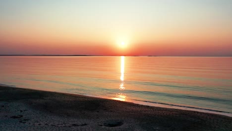 Blick-Auf-Den-Sonnenuntergang-Am-Meer-Beim-Spazierengehen-Am-Strand-Mit-Hell-Leuchtender-Sonne,-Die-Farbenfrohe-Rote,-Orange,-Violette-Und-Gelbe-Reflexe-Auf-Friedliche,-Plätschernde-Wellen-Des-Meeres-Mit-Wunderschönem-Himmel-Wirft