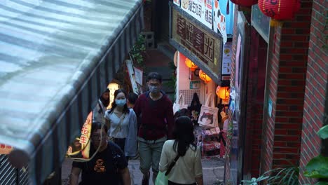 Gente-Deambulando-Por-El-Laberinto-De-Calles-Estrechas-Y-Escaleras-Empinadas,-Explorando-El-Encantador-Pueblo-De-Montaña-De-Jiufen-Con-Tiendas-De-Souvenirs-Culturales-Y-Puestos-De-Comida-Local-A-Lo-Largo-Del-Camino