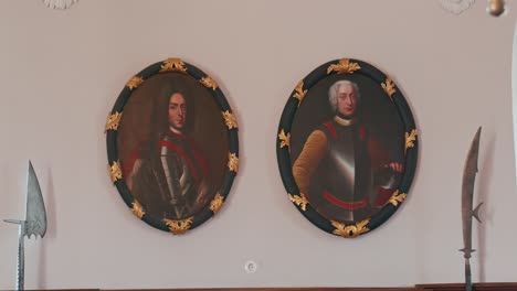 Historische-Porträts-Von-Adligen-Mit-Vergoldeten-Rahmen-Und-Hellebarden,-Ausgestellt-Im-Rittersaal-Des-Schlosses-Trakoscan