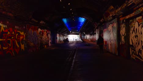 Walking-Through-Dark-Underground-Tunnel-in-London,-Graffiti-Art-on-Walls