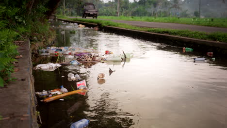 Verschmutzte-Wasserstraße-Mit-Vorbeifahrendem-Verkehr-Auf-Dem-Land,-Balis-Plastikproblem