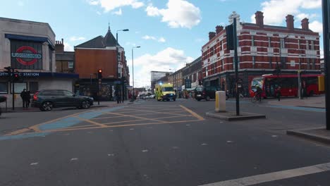 Una-Ambulancia-Del-Reino-Unido-Acelera-A-Través-De-Una-Concurrida-Intersección-De-Londres-Con-Las-Luces-Y-La-Sirena-Encendidas.