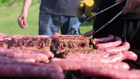 Hand-Mit-Zange-Wendet-Würstchen-Grillen-Im-Freien