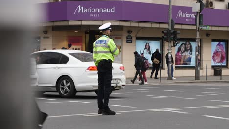 Oficial-De-Policía-Parisino-Dirigiendo-El-Tráfico-En-Una-Esquina-De-Una-Calle-Muy-Transitada-Durante-El-Día,-Bucarest,-Rumania