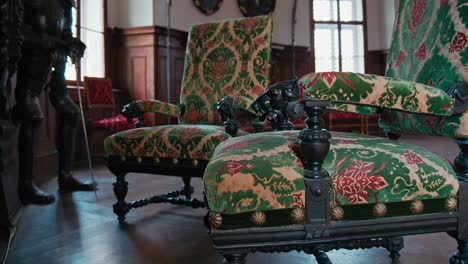 Luxurious-upholstered-chairs-with-vibrant-floral-designs-beside-an-armor-display-in-Trakoscan-Castle's-hall